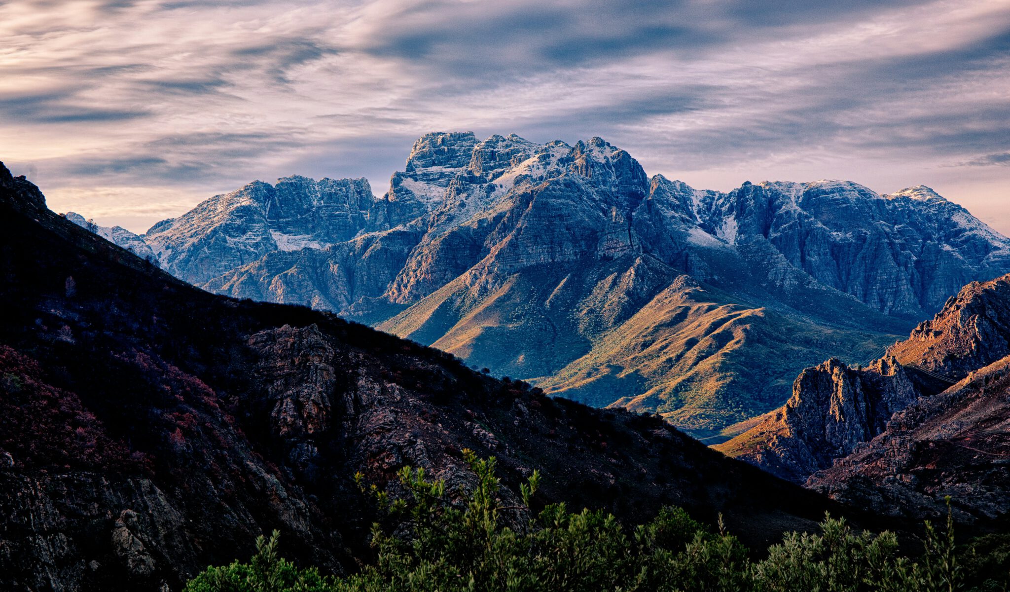 Majestic mountain range with sunlit peaks under a cloudy sky